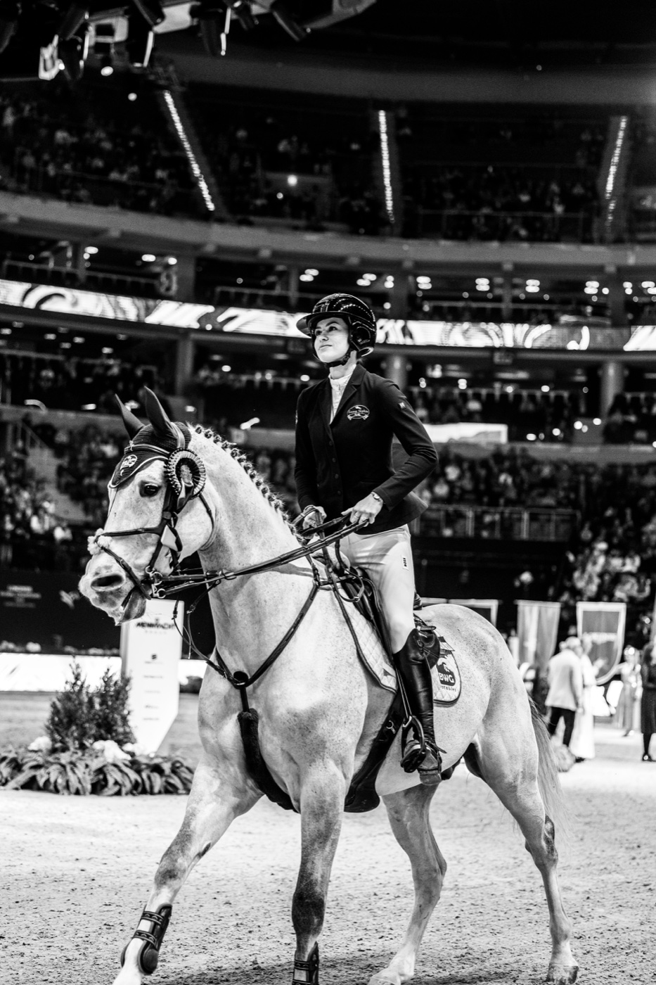 Black-and-white photograph of Emma Sophia Španko on horseback in a packed arena during an international competition