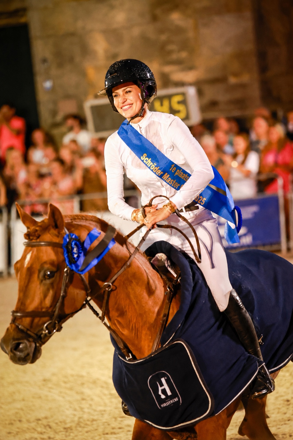 Emma Sophia Španko smiling on horseback, wearing a winner's sash after a competition win