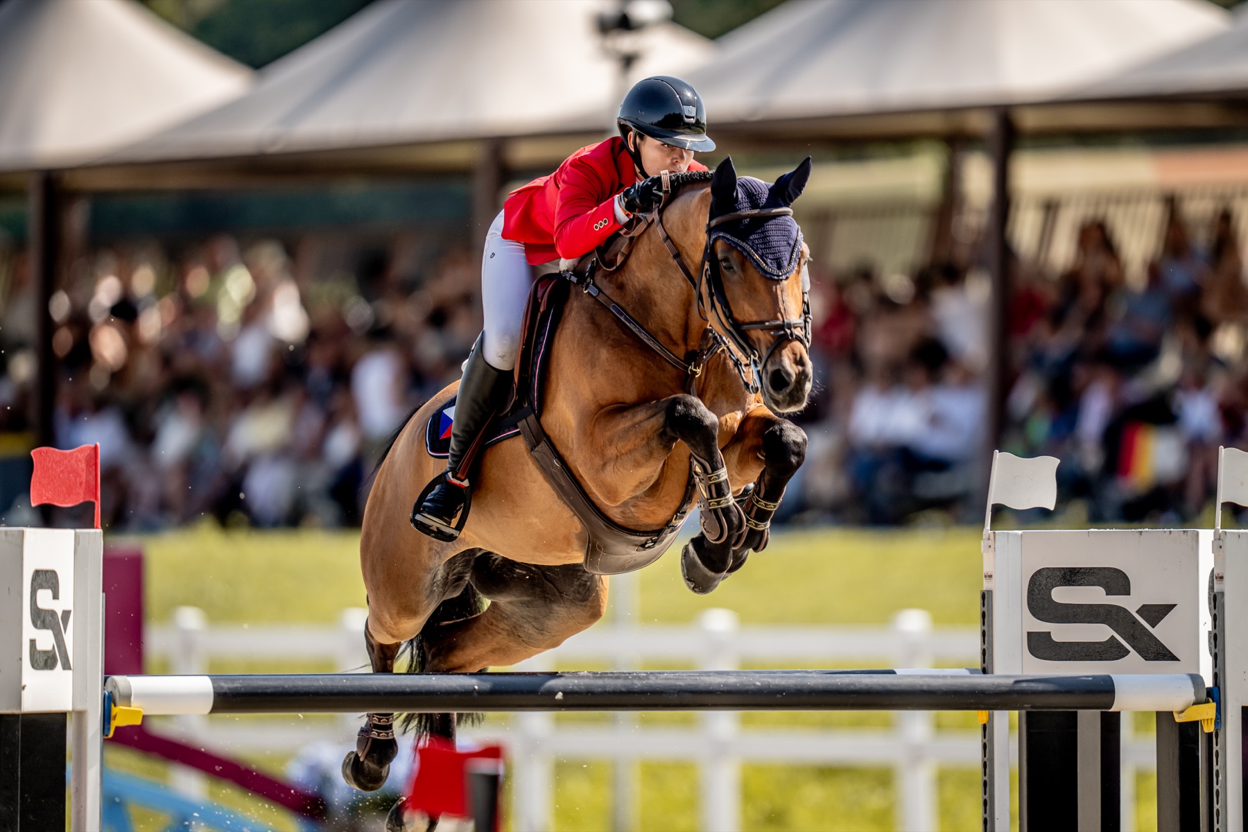 Emma Sophia Španko jumping a fence in Czech national colours at a 2023 show jumping competition