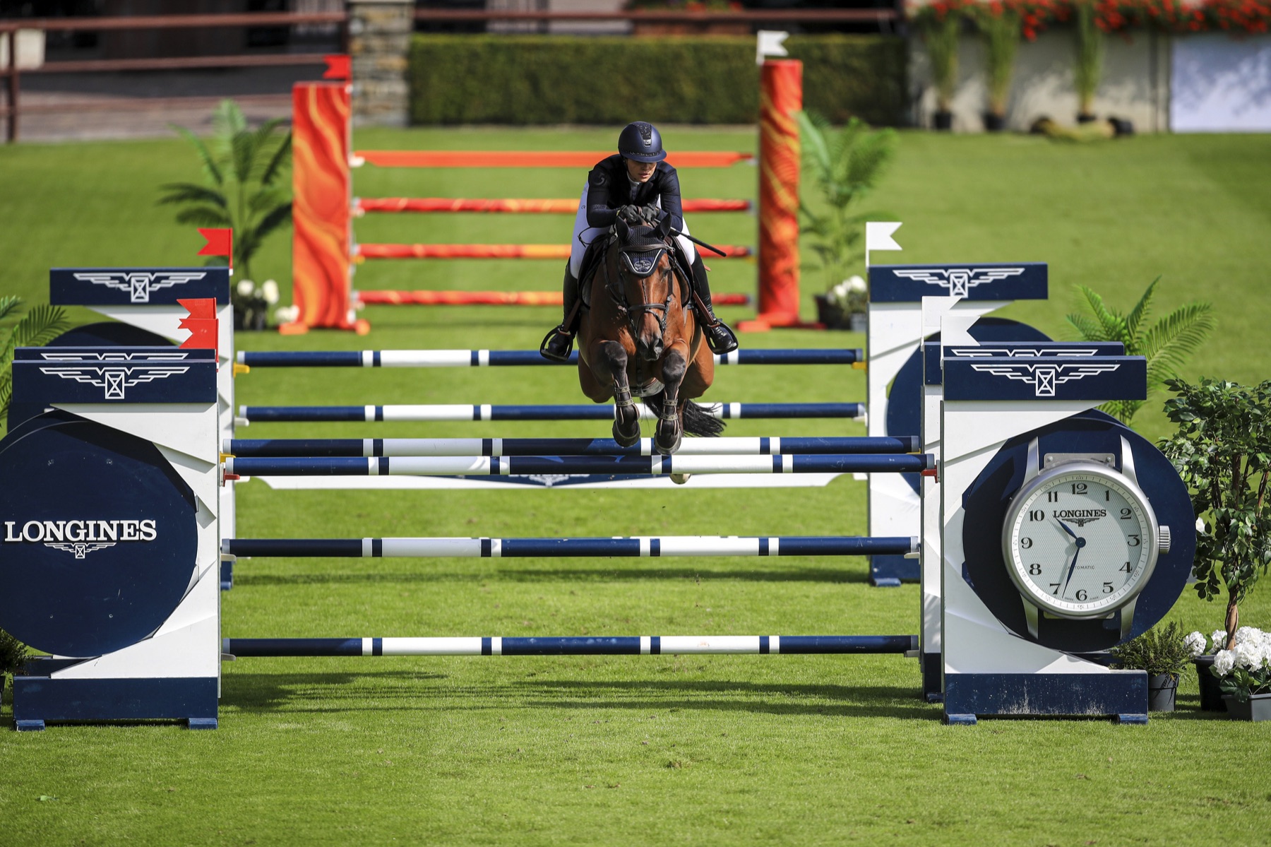 Emma Sophia Španko jumping a fence beside a large Longines clock